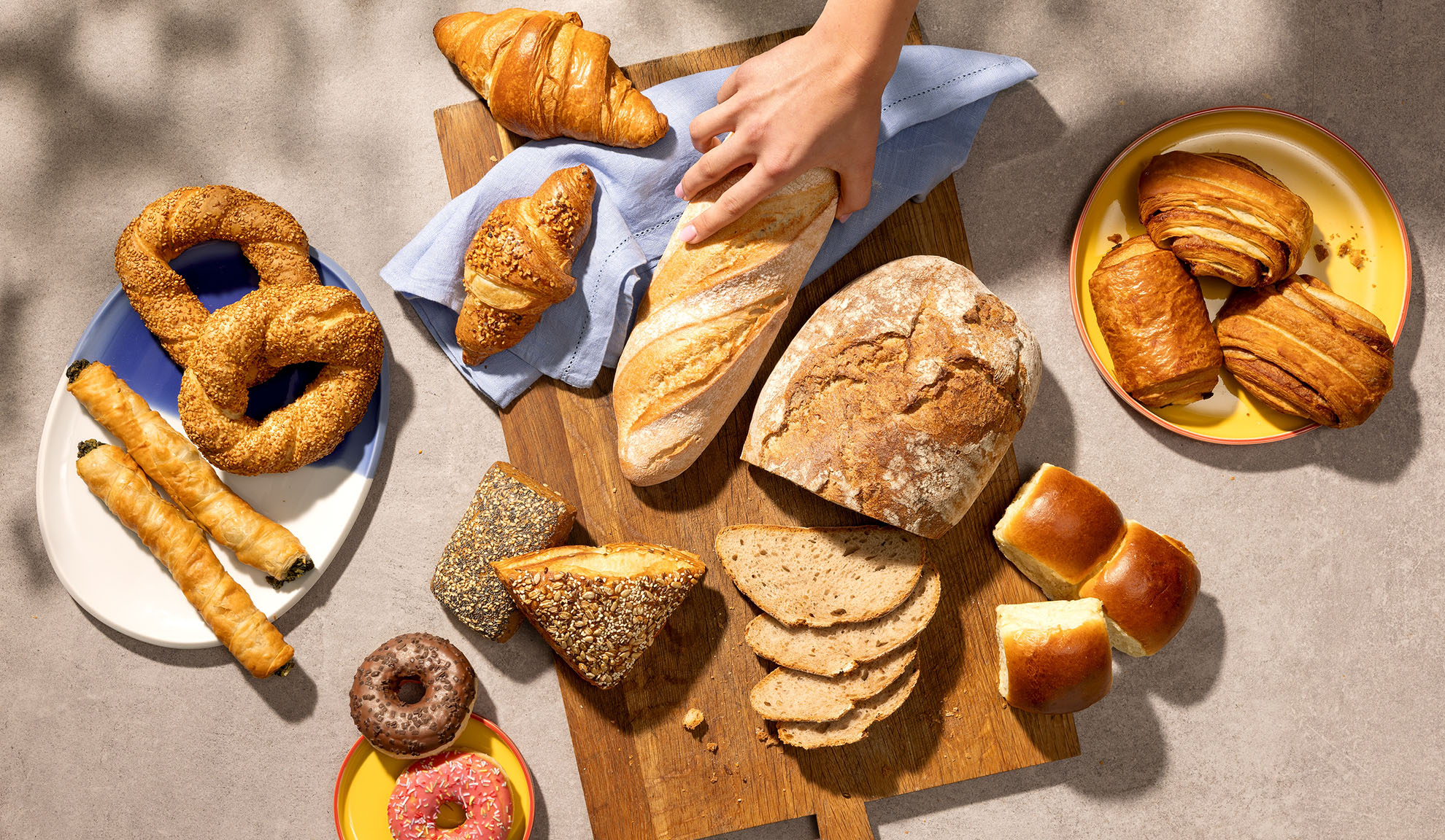 Assortimento di prodotti da forno freschi, inclusi pane, croissant, pasticcini e ciambelle su un tavolo.