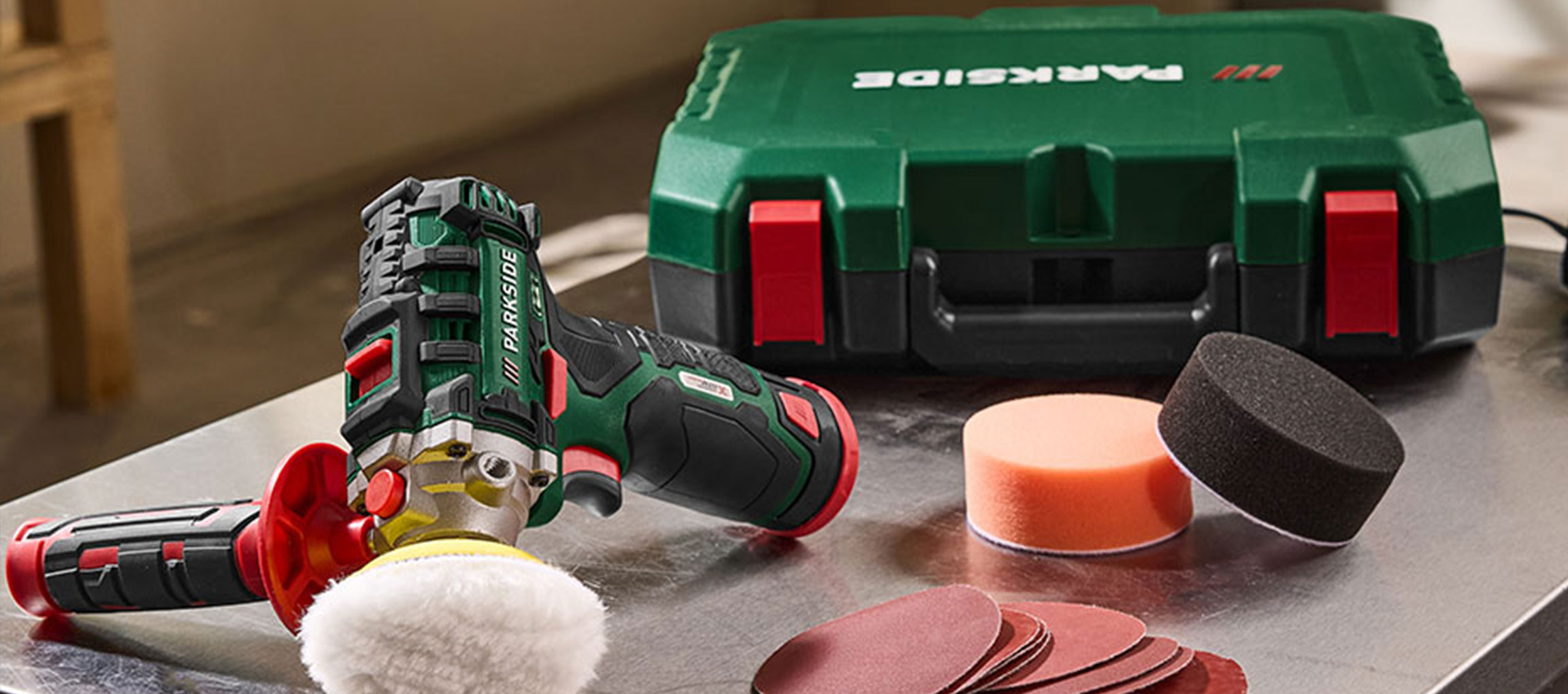 Lucidatrice con accessori e valigetta verde per attrezzi su superficie metallica.