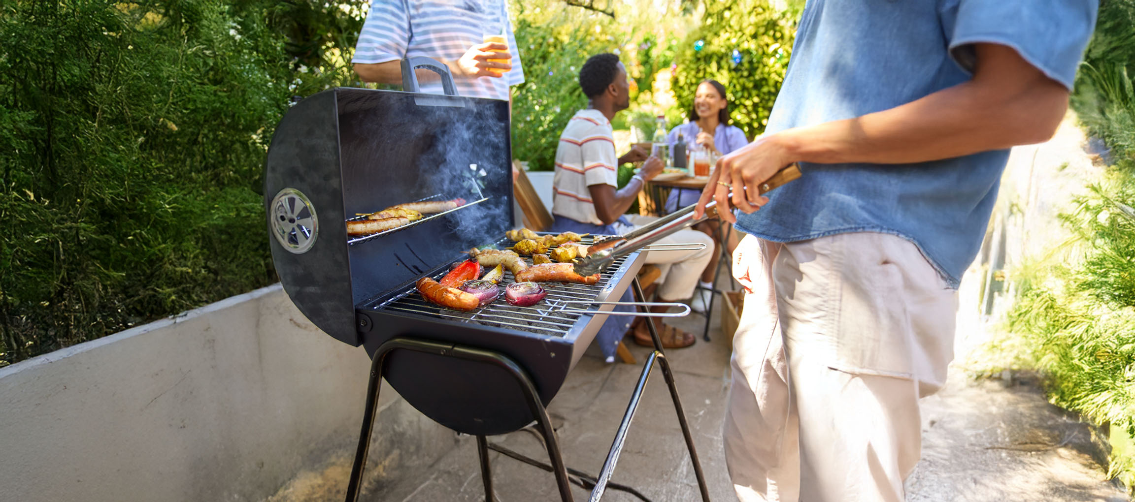 Un barbecue a carbone con salsicce e verdure grigliate.