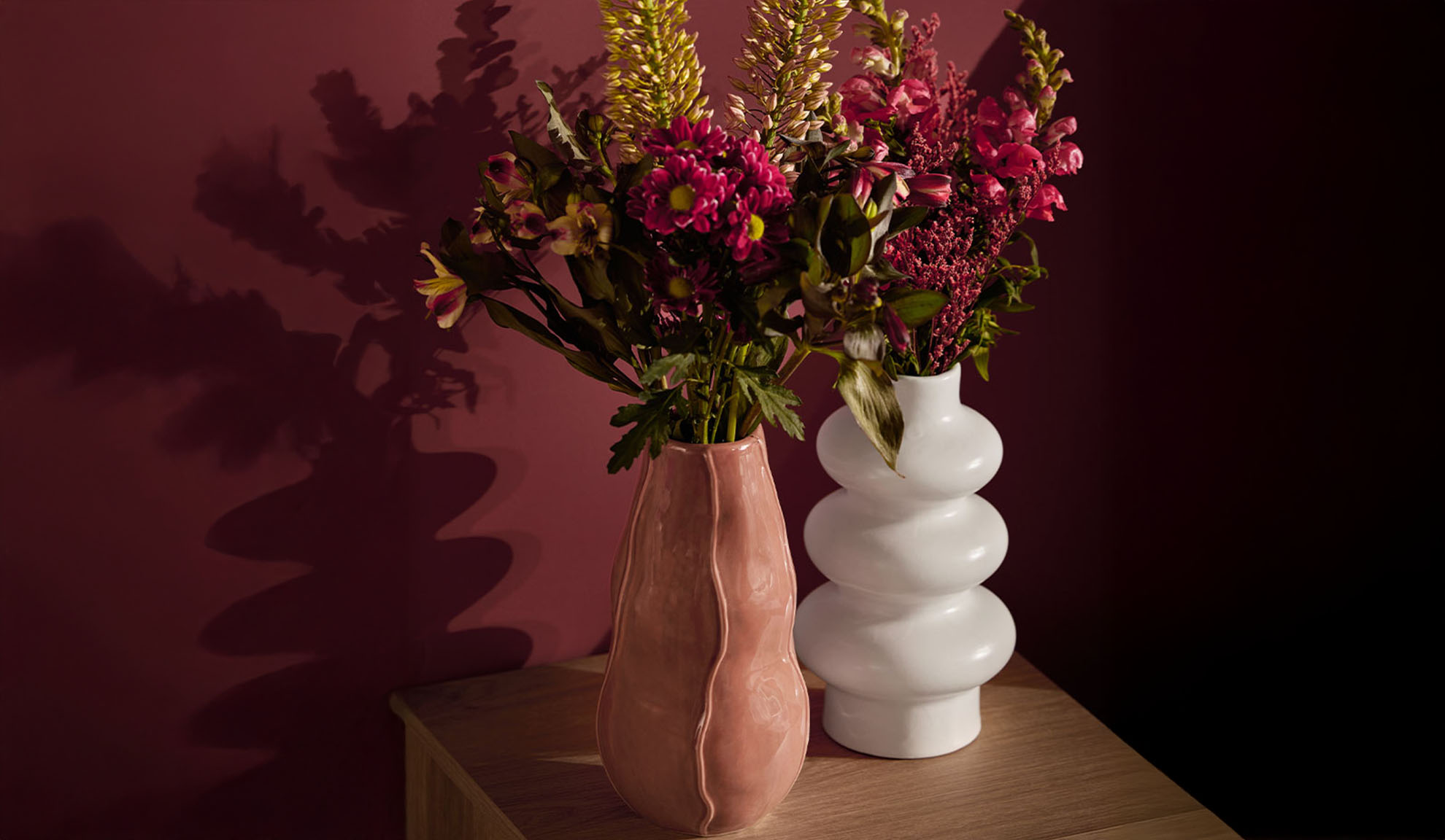 Due vasi con fiori colorati su un tavolo di legno.
