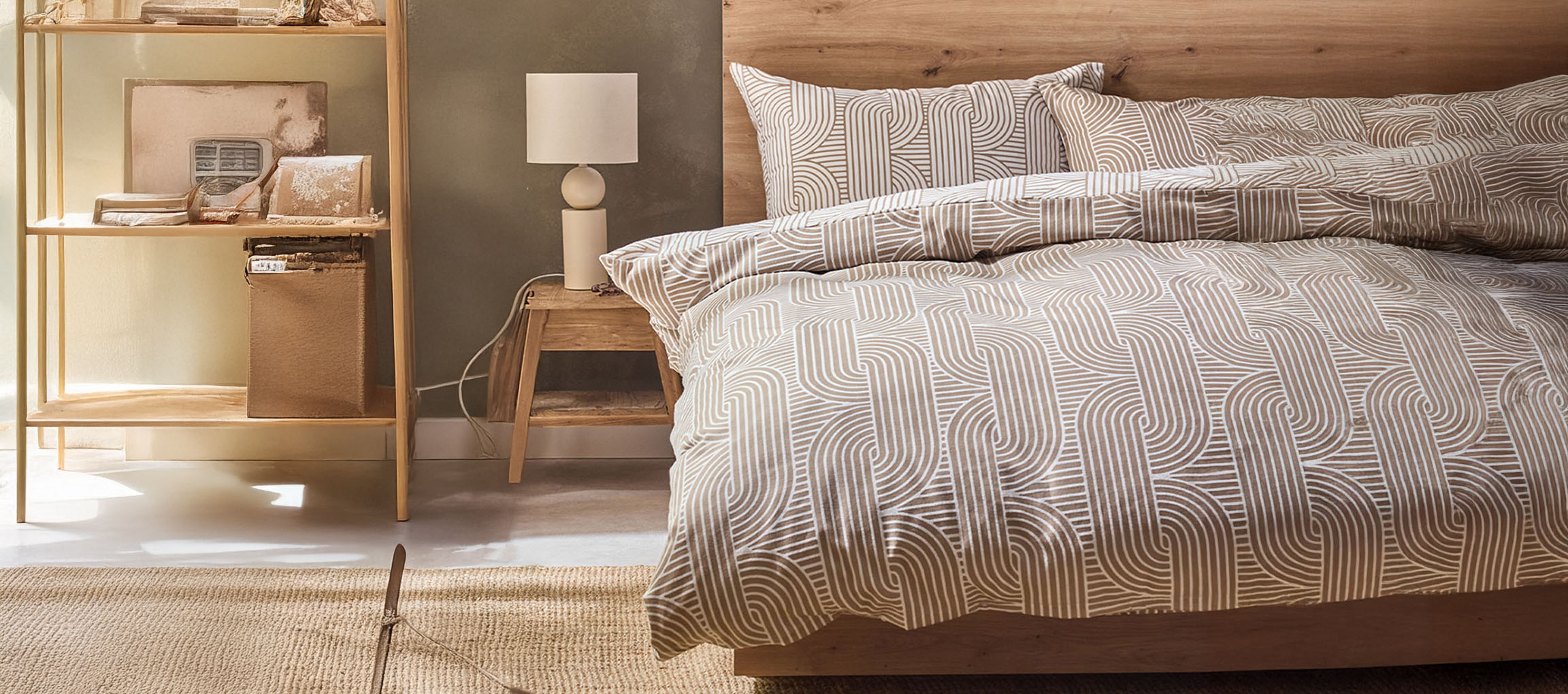 Camera da letto con letto in legno, copripiumino fantasia, comodino e scaffale.