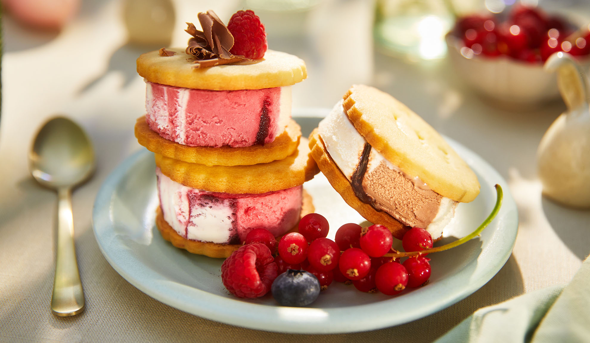 Sandwichs glacés aux baies sur une assiette bleu clair dans un cadre extérieur ensoleillé.