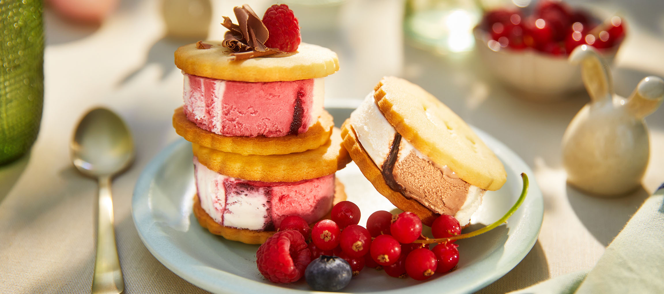 Sandwichs glacés aux baies sur une assiette bleu clair dans un cadre extérieur ensoleillé.