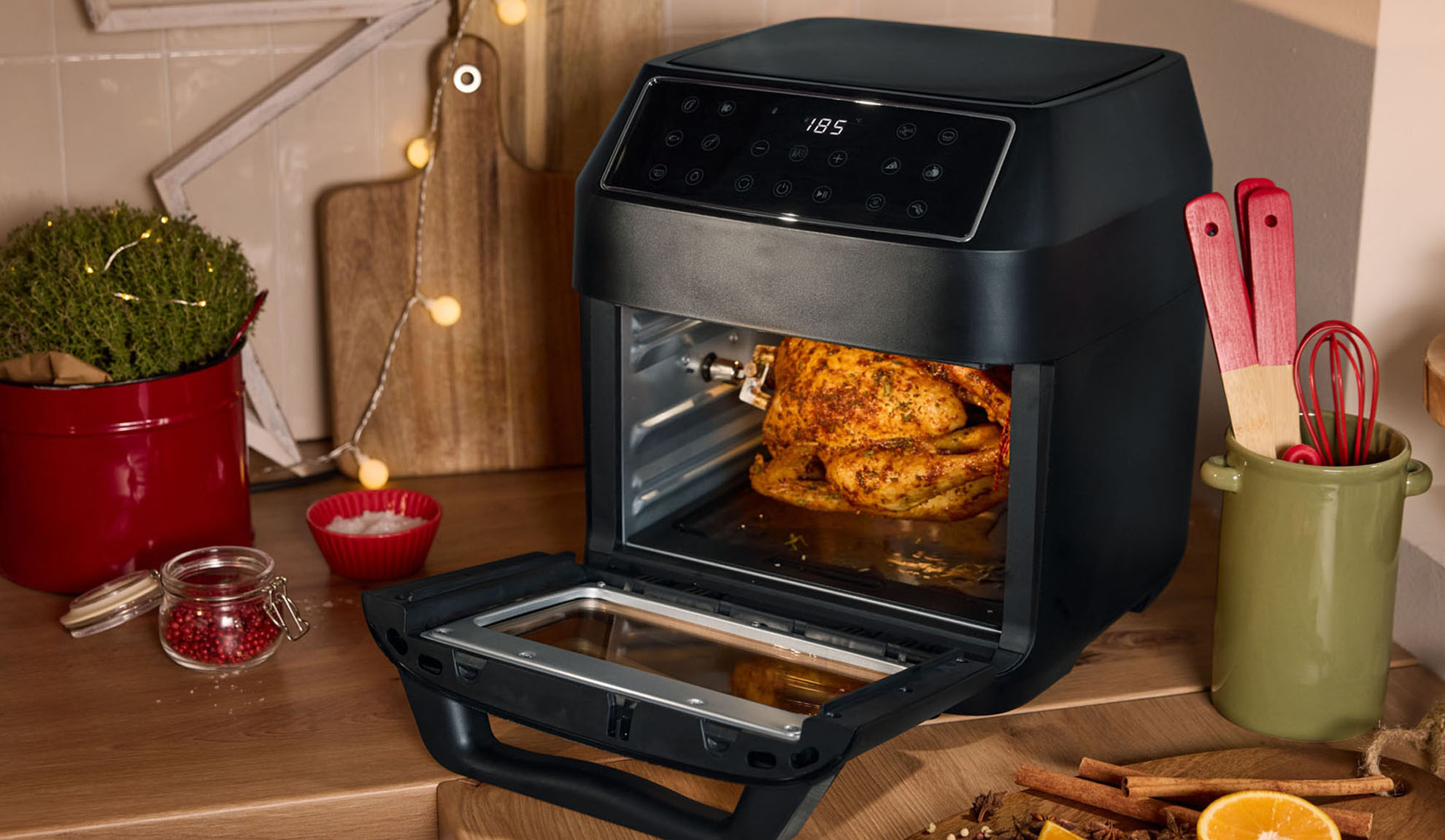 Friteuse à air avec poulet rôti, épices et décorations de Noël dans la cuisine.