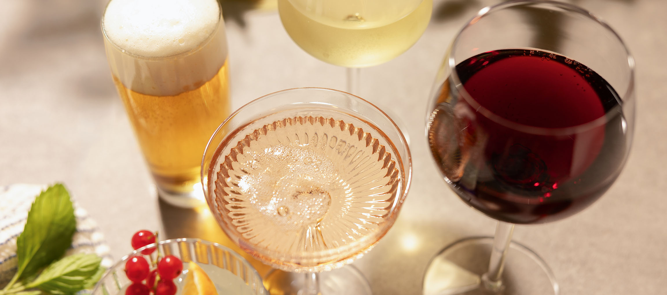 Bière, vin rosé et vin rouge dans des verres, avec des baies et de la menthe.