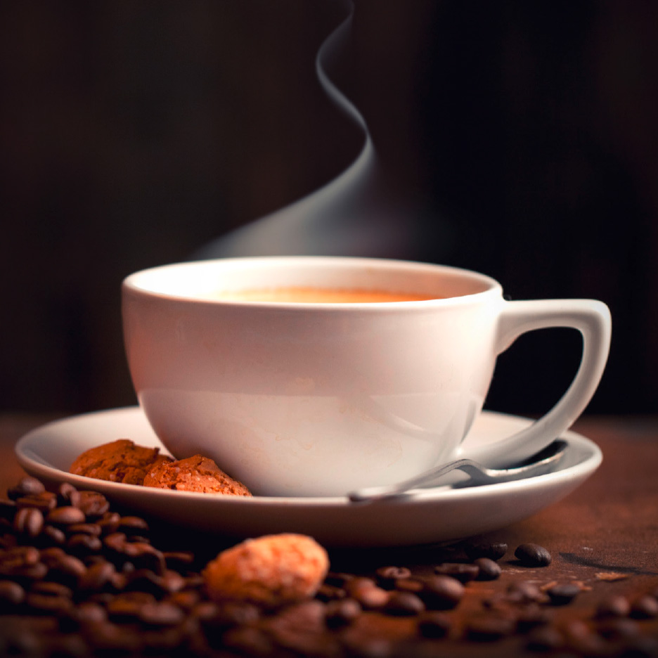Dampfende Kaffeetasse mit Keksen und verstreuten Kaffeebohnen.