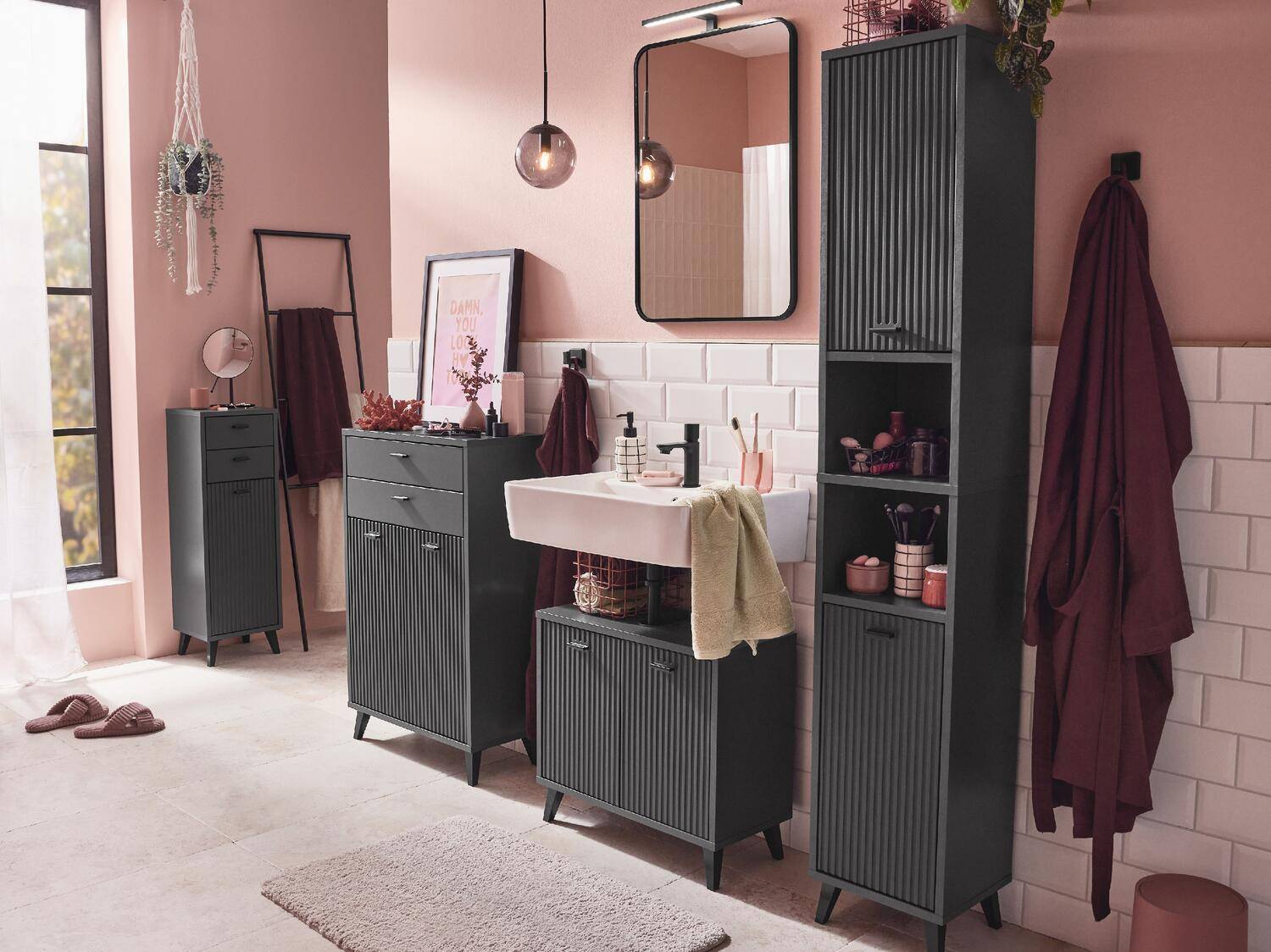 Ein modernes Badezimmer mit gerillten grauen Möbeln, einem weißen Waschbecken, einem Spiegel und rosa Wänden.