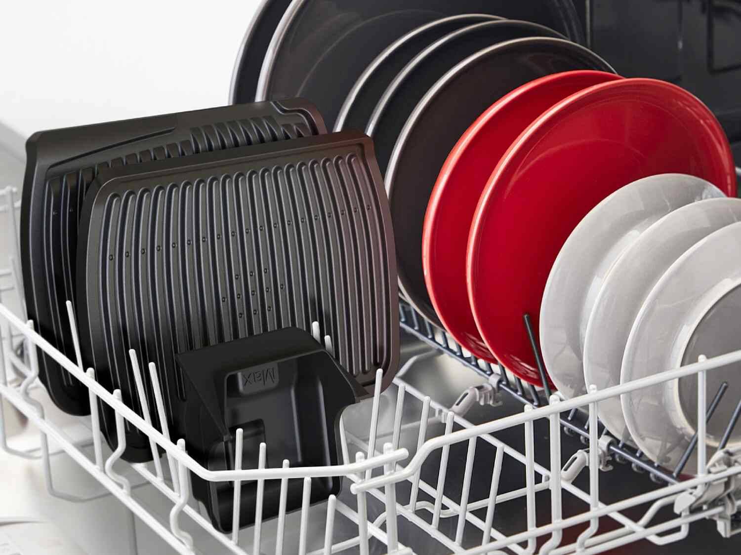 Schwarze, rote und graue Teller sowie zwei schwarze Ofenroste in einem Geschirrspüler.