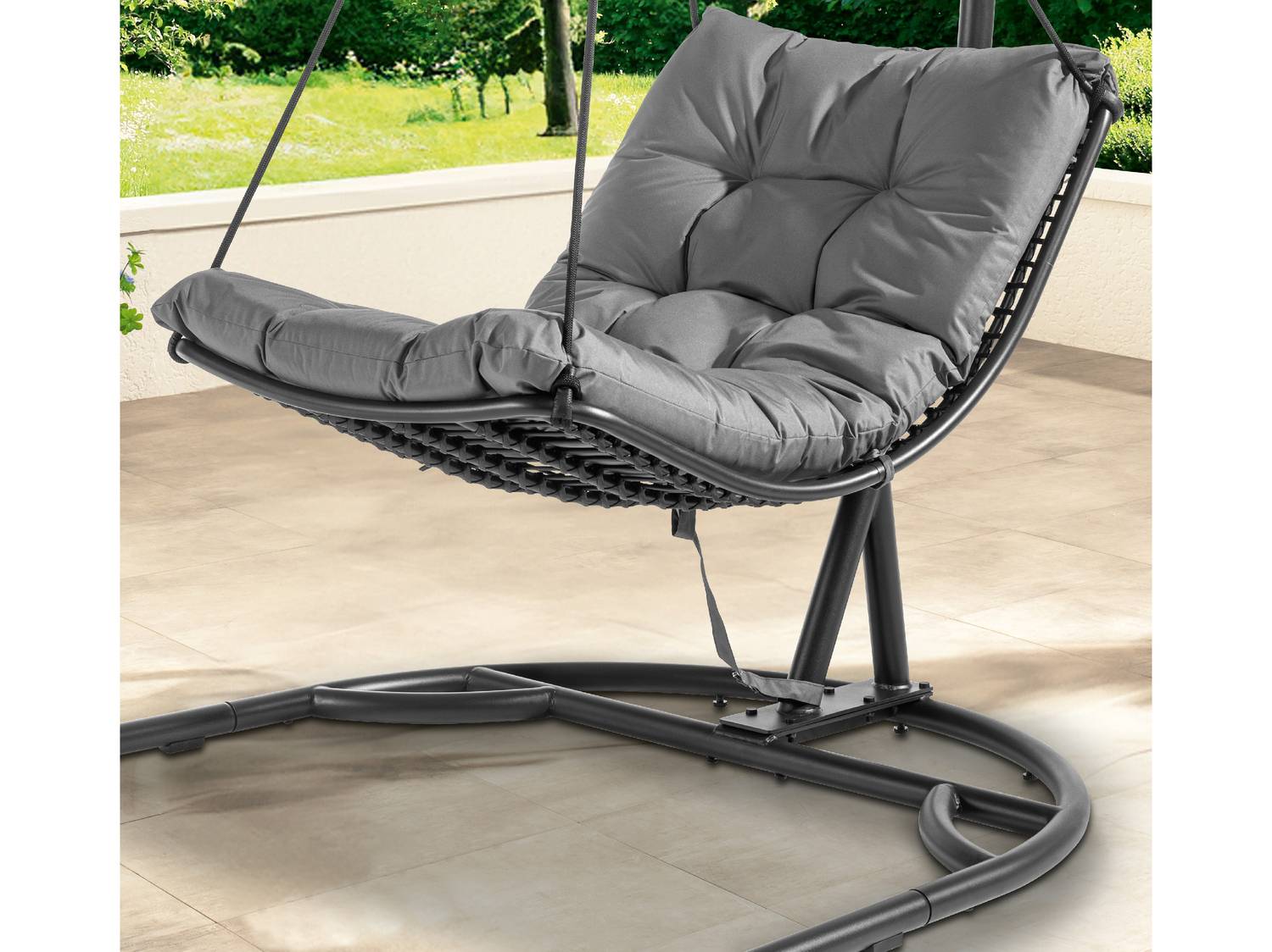 Sedia sospesa grigia con cuscini morbidi su una terrazza soleggiata.