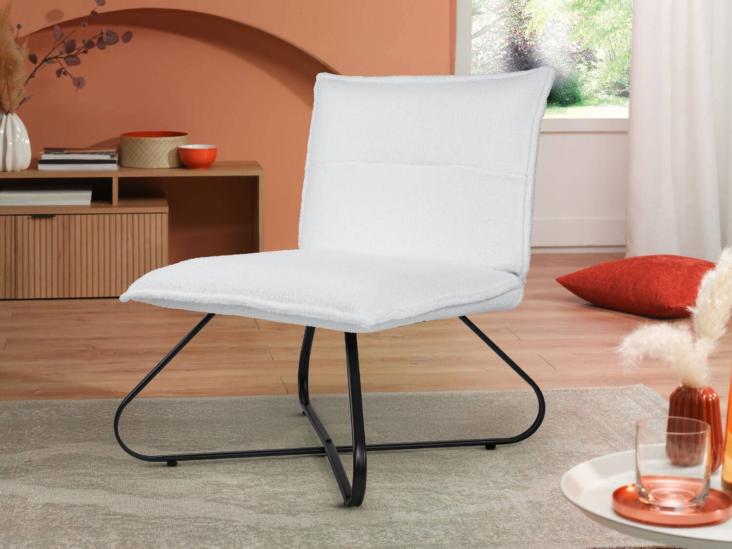 Weißer Bouclé-Stuhl mit schwarzem Metallgestell in einem modernen Wohnzimmer.