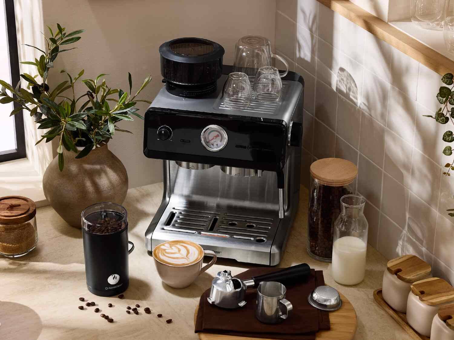 SilverCrest Kaffeemaschine mit Mühle, Kaffeetasse und Zubehör auf einer Küchenarbeitsplatte.