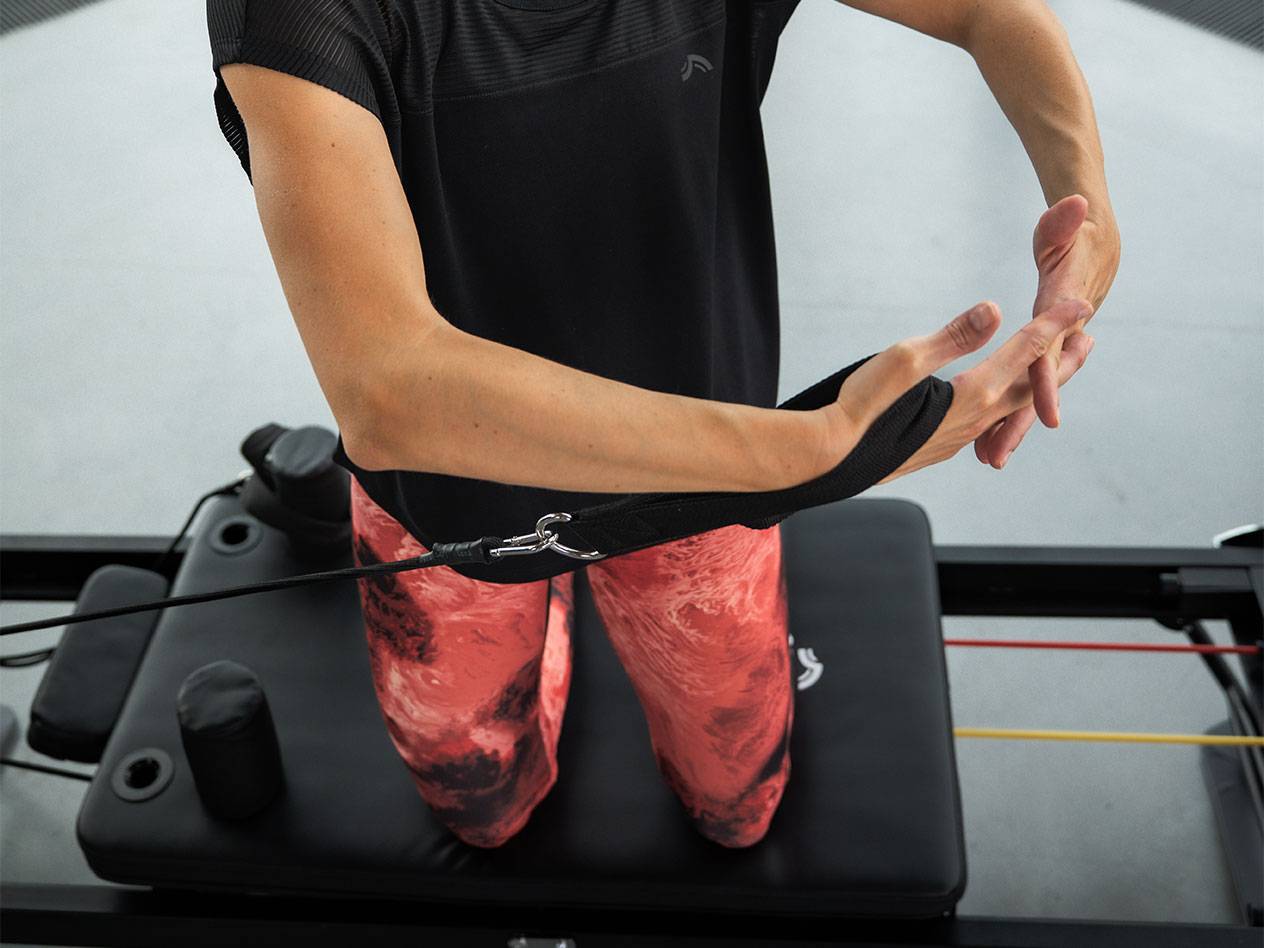 Donna che si allena con fasce di resistenza su una macchina Pilates.