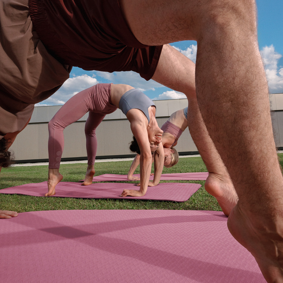 Persone che fanno yoga all'aperto su tappetini da yoga, in abbigliamento sportivo.