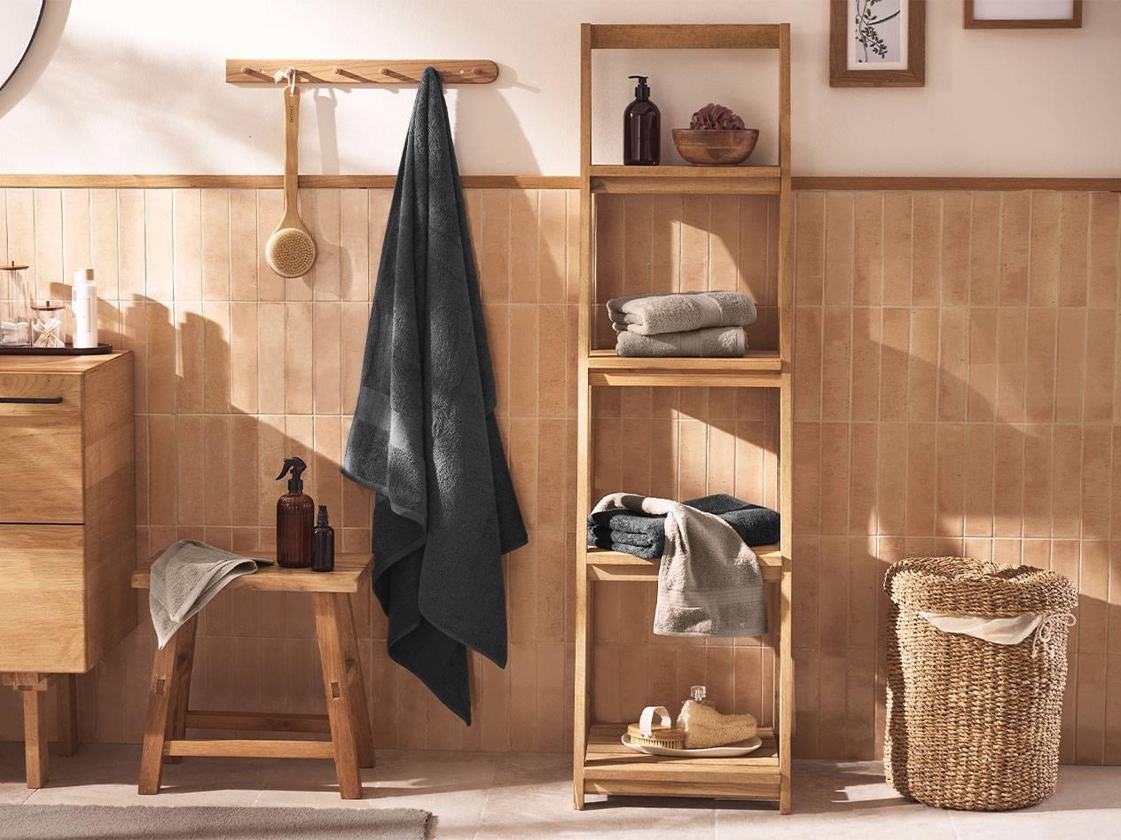Salle de bain avec serviettes grises, étagères en bois et accessoires de bain.