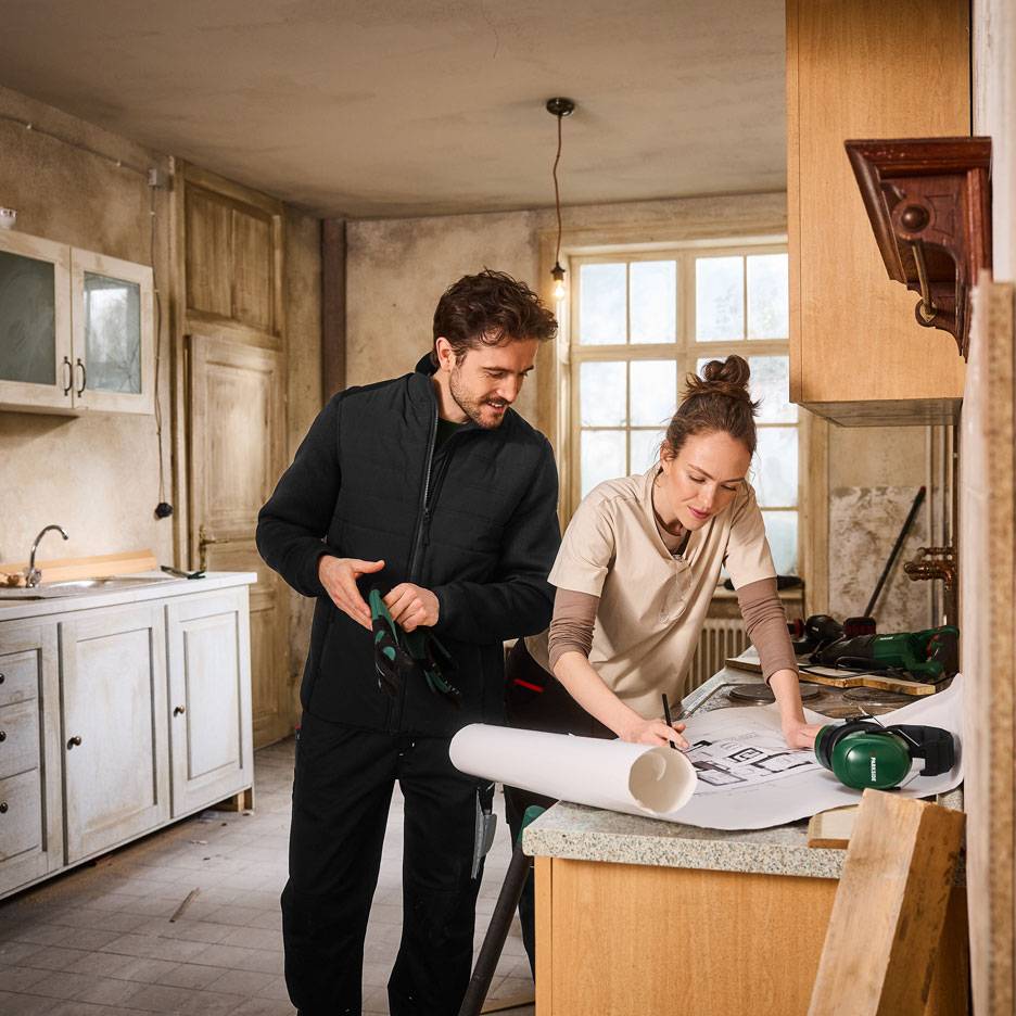 Homme et femme en tenue de travail planifiant une rénovation de cuisine.