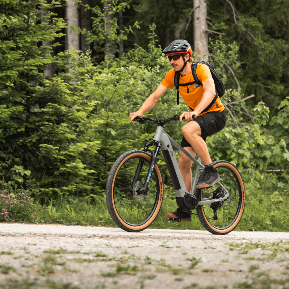 Uomo che guida una e-bike su un sentiero nel bosco.