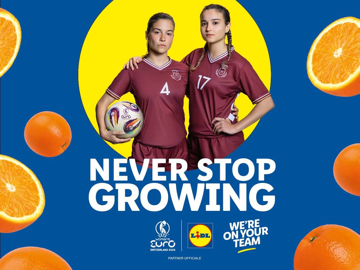 Due giocatrici di calcio Lidl sorridenti, che tengono un pallone da calcio, con arance intorno a loro.