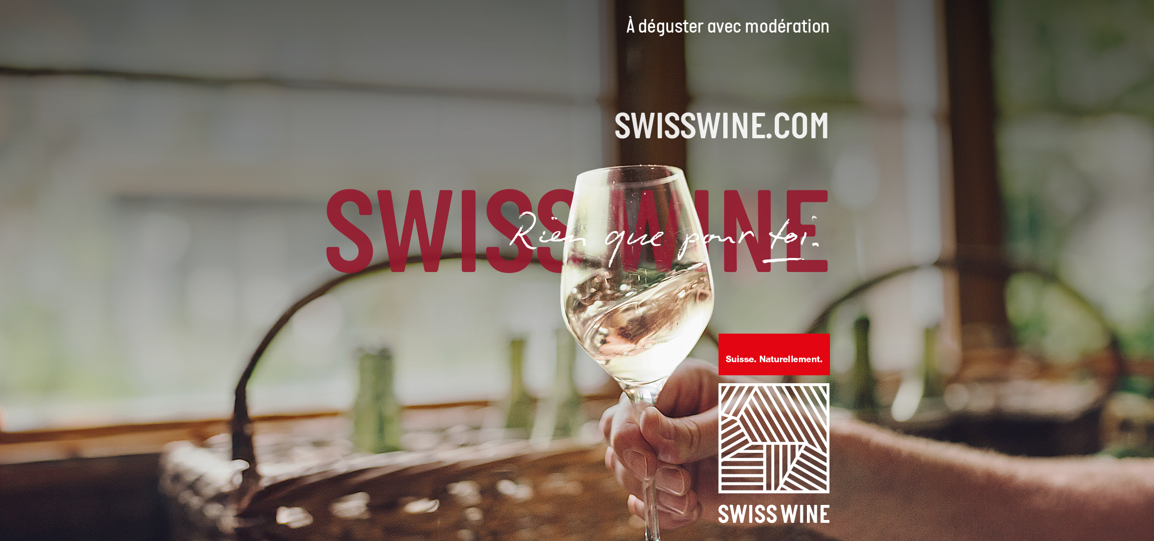 Un verre de vin blanc avec le logo Swiss Wine et le slogan 'Suisse. Naturellement.'