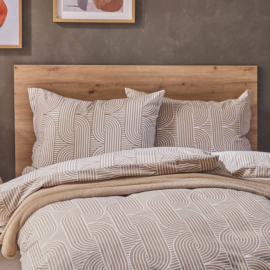Biancheria da letto con motivo geometrico marrone e bianco, una morbida coperta su un letto in legno.