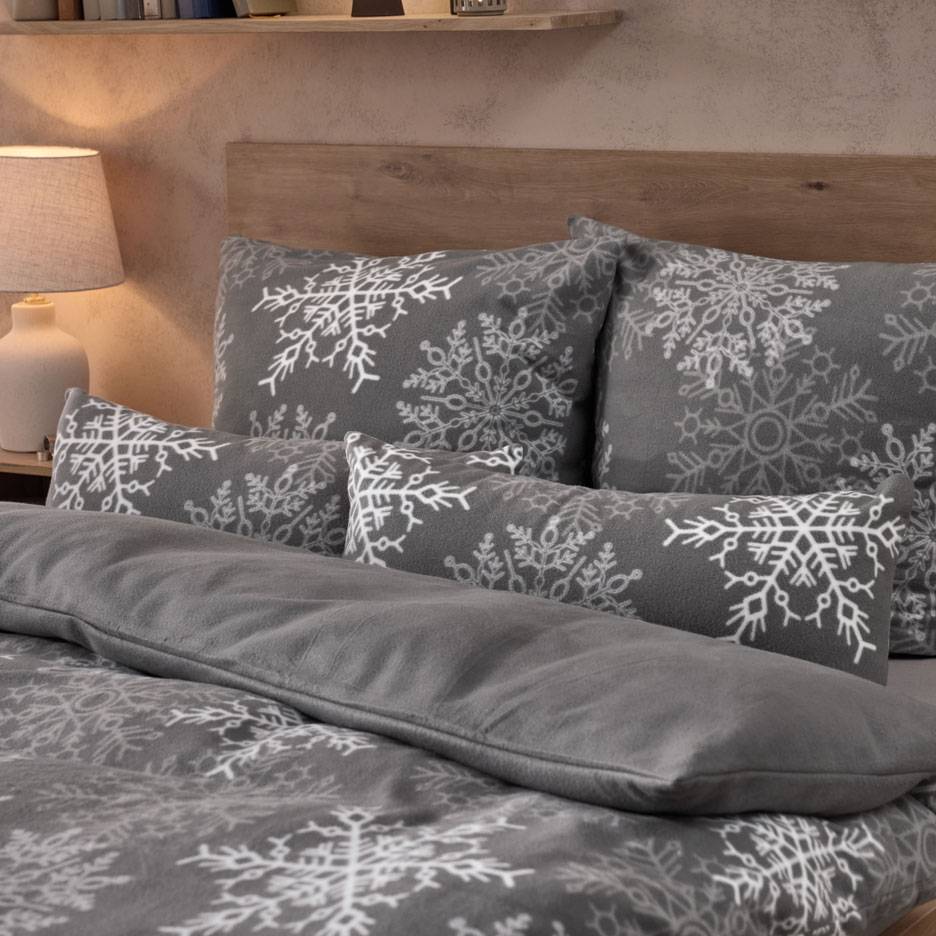 Biancheria da letto grigia con fiocchi di neve bianchi, con cuscini e una coperta soffice.