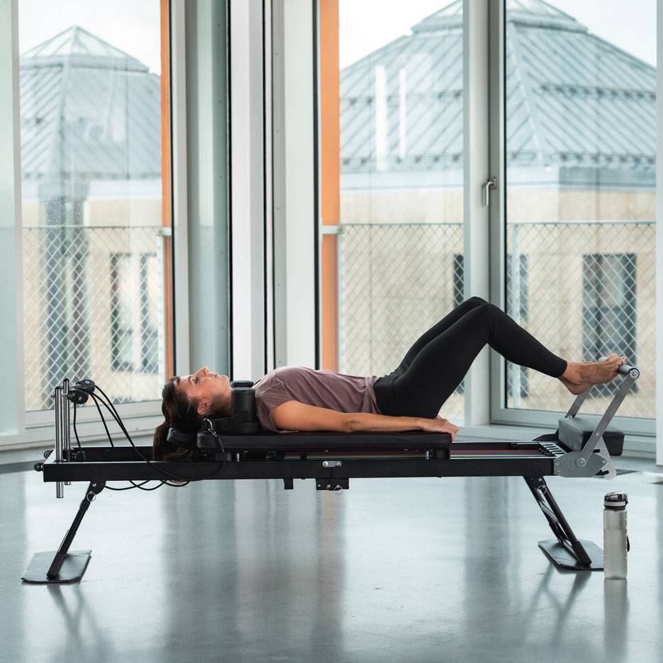 Donna che fa esercizi di Pilates su una macchina reformer.