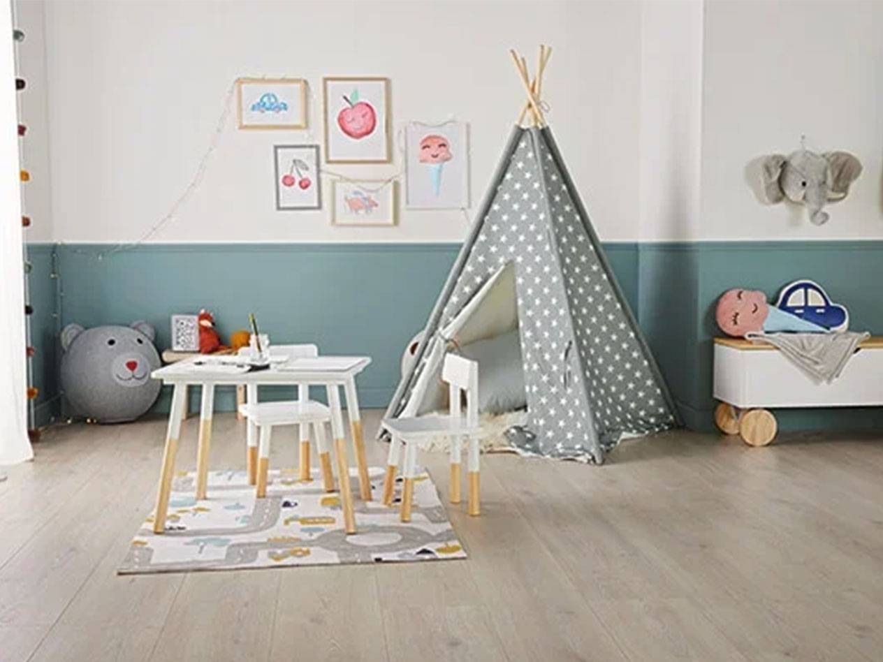 Chambre d'enfant avec une tente tipi, une table et des chaises, un coffre à jouets et des tableaux au mur.