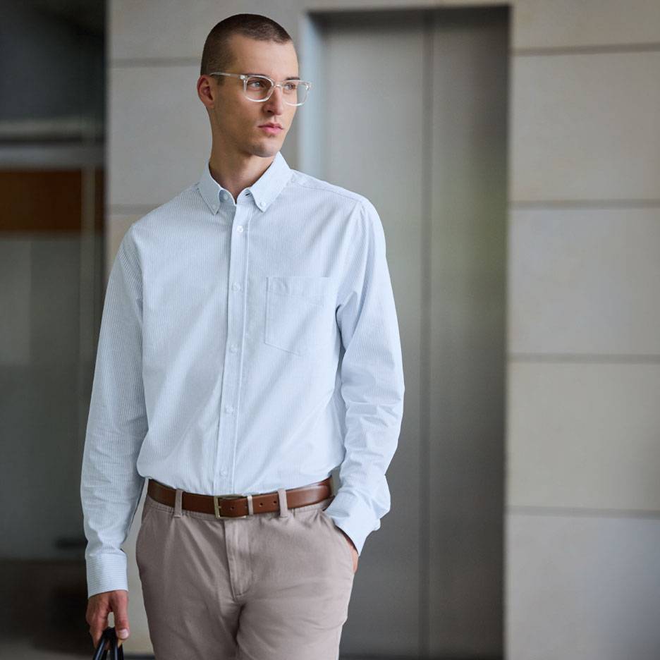Homme en chemise rayée bleu clair et pantalon beige avec une ceinture marron.