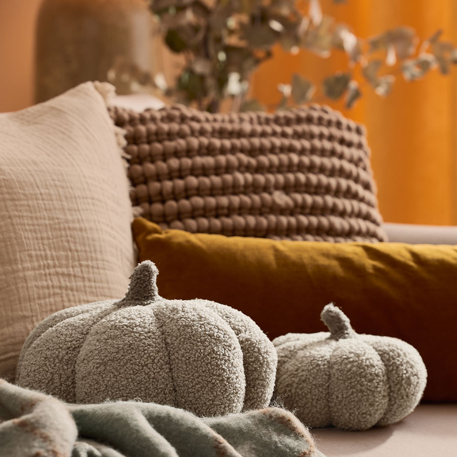 Gemütliches Sofa mit Zierkissen und zwei weichen Kürbiskissen.