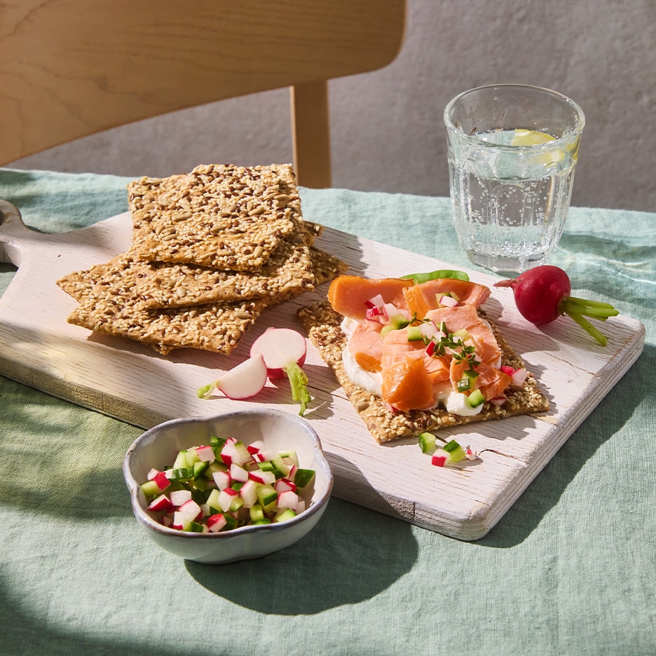 Samen-Cracker mit Räucherlachs, Frischkäse, Radieschen und Gurken.