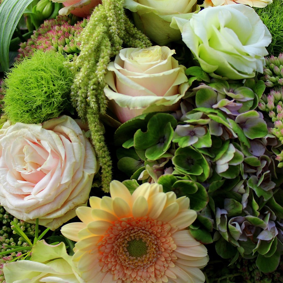 Nahaufnahme eines Blumenstraußes mit rosa und weißen Rosen, Gerbera und grünem Beiwerk.