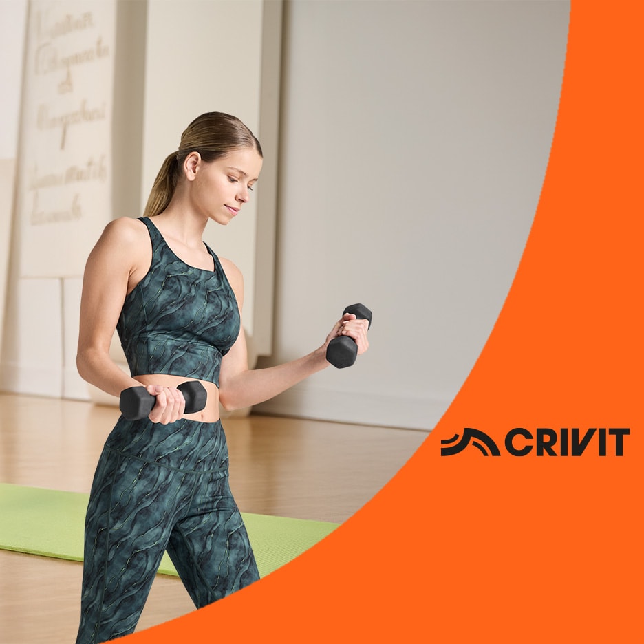 Femme en tenue de sport vert foncé avec des haltères, sur un tapis de yoga.