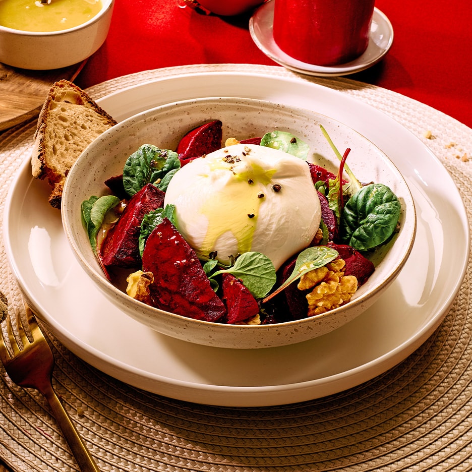 Burrata-Salat mit Roter Bete, Walnüssen und Spinat, dazu eine Scheibe Brot.