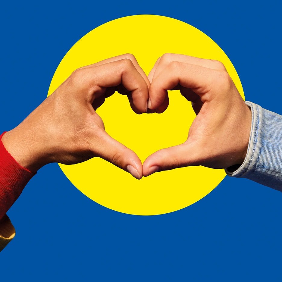 Hände formen ein Herz vor blauem Hintergrund und gelbem Kreis.