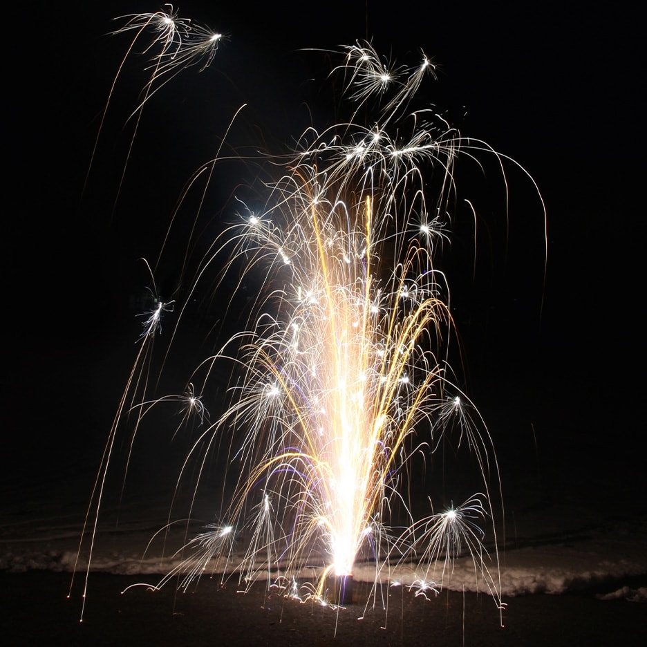 Feuerwerk explodiert in der Dunkelheit mit goldenen und weißen Funken.