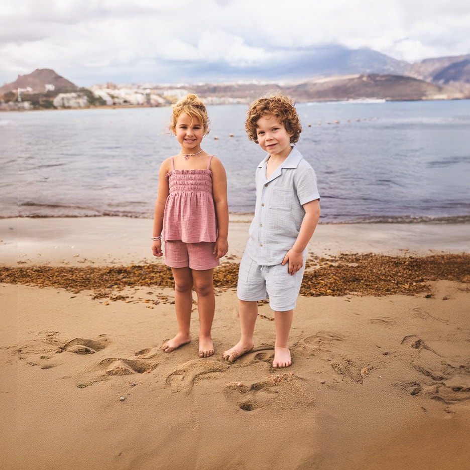 Kinder in rosa und hellblauem Sommer-Set am Strand.