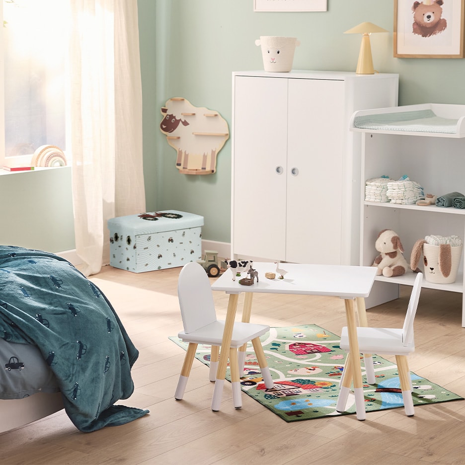 Chambre d'enfant avec table et chaises, commode à langer, armoire et coffre à jouets.