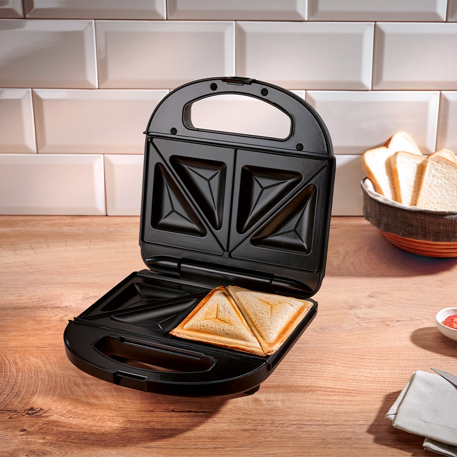 Sandwichmaker mit einem fertigen Sandwich auf einer Holzarbeitsplatte