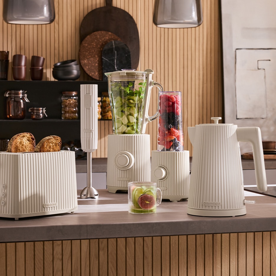 Appareils de cuisine crème avec grille-pain, mixeur, mixeur plongeant et bouilloire sur un comptoir.