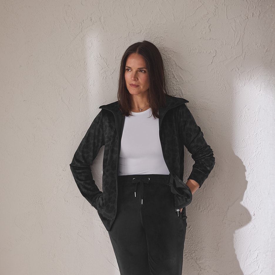 Frau in schwarzer Sportjacke mit Leopardenmuster, weißem Top und schwarzer Hose.