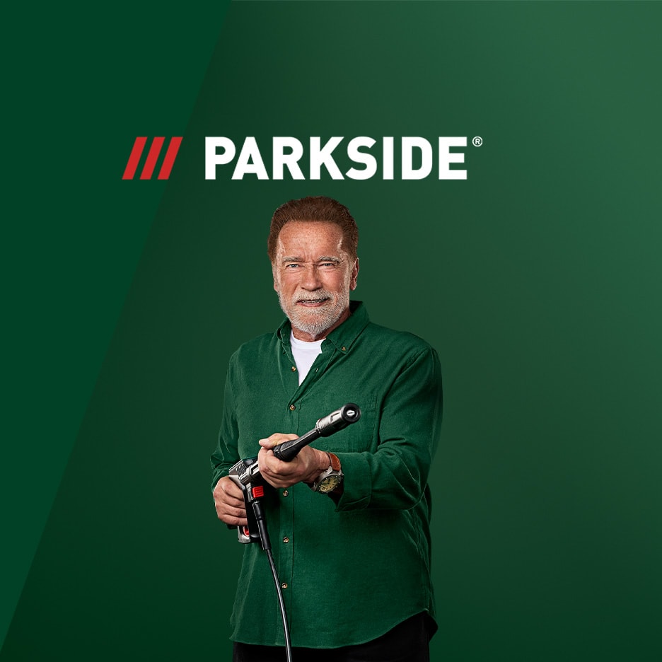 Arnold Schwarzenegger lächelt und hält einen Hochdruckreiniger vor grünem Hintergrund mit Logo.