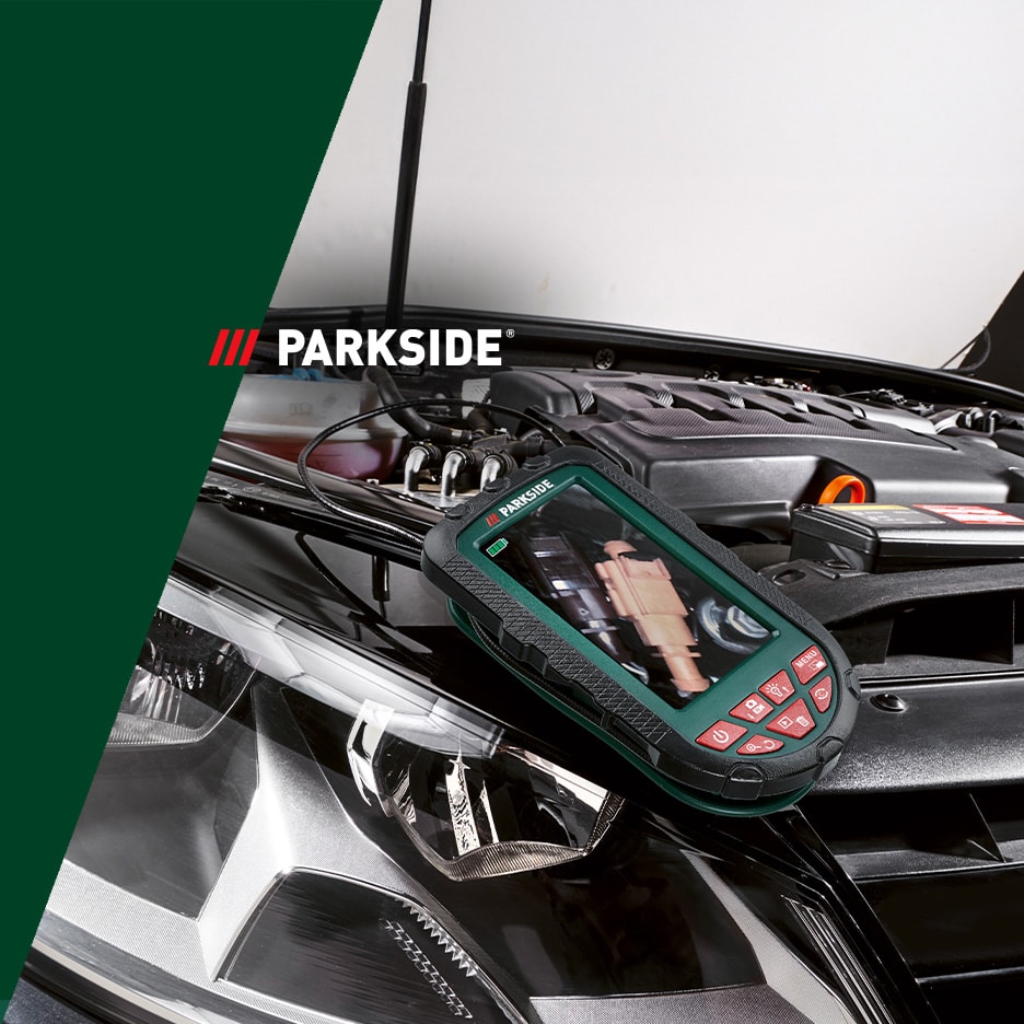 Ein digitales Endoskop liegt auf dem geöffneten Motor eines Autos und zeigt ein mechanisches Teil.