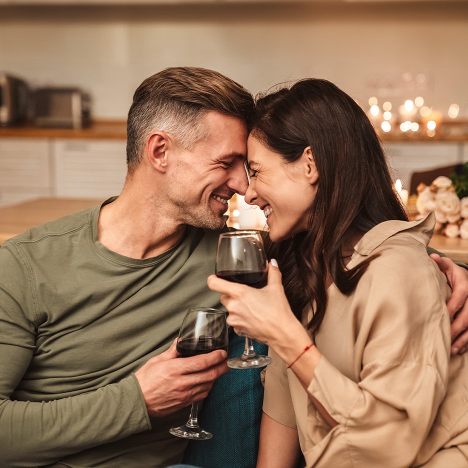 Glückliches Paar genießt Rotwein bei romantischem Abend.