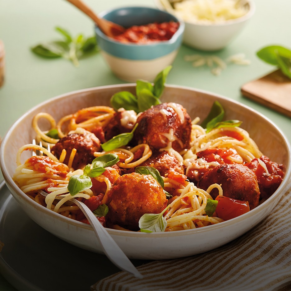 Spaghetti mit Fleischbällchen, Tomatensauce und Basilikum in einer Schüssel.