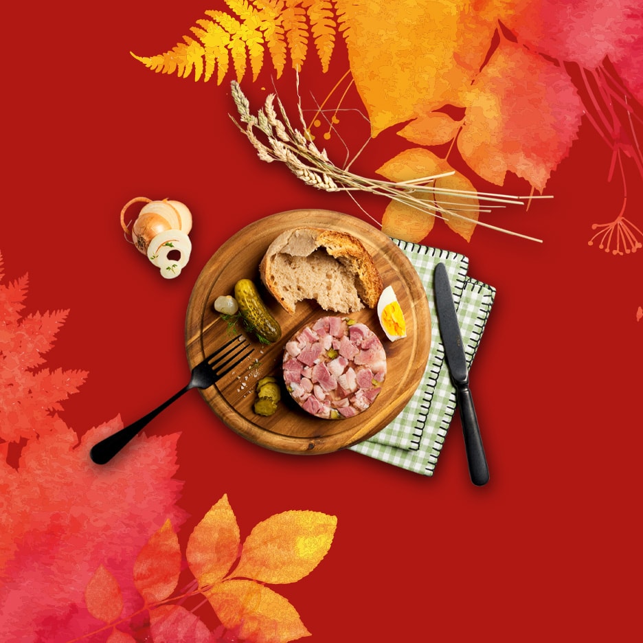 Wurstplatte mit Brot, Essiggurken und gekochtem Ei auf rotem Hintergrund mit Herbstblättern.