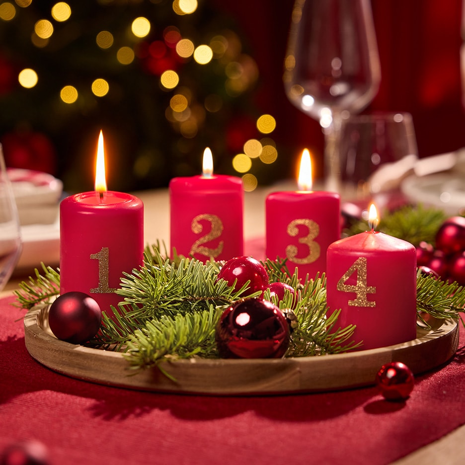 Adventskranz mit vier roten nummerierten Kerzen und Weihnachtsdekoration.