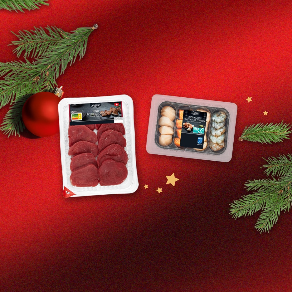 Deluxe Fleisch- und Fischplatten auf festlichem rotem Hintergrund mit Tannenzweigen.