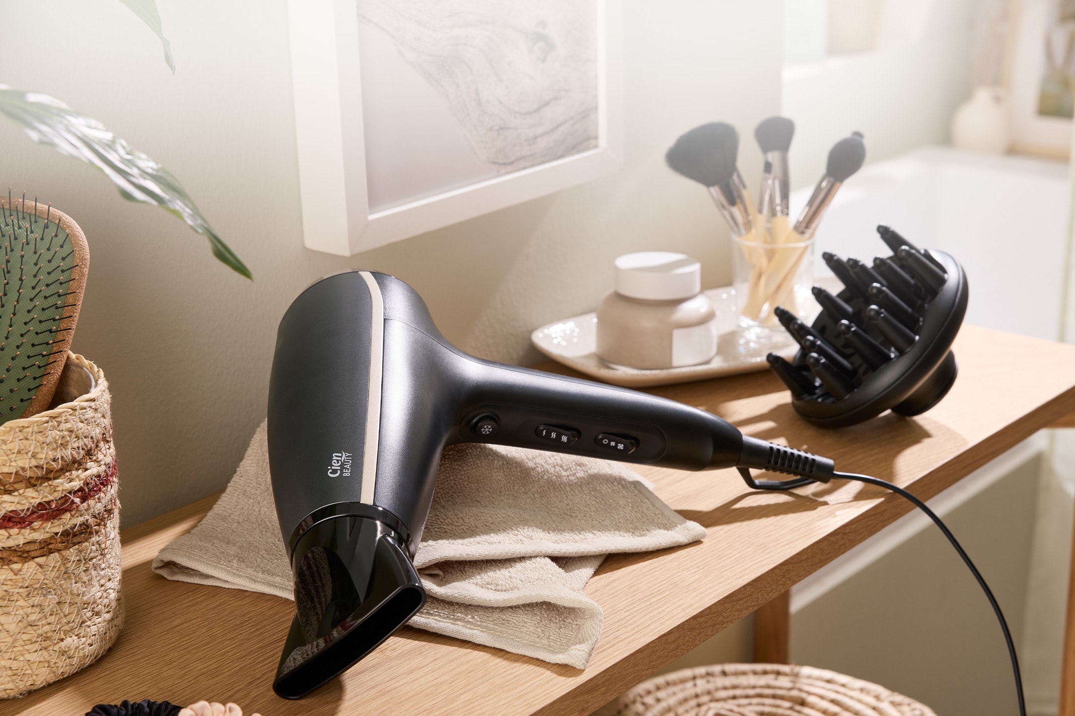 Sèche-cheveux noir avec diffuseur et brosse sur une table en bois, avec des produits de beauté.