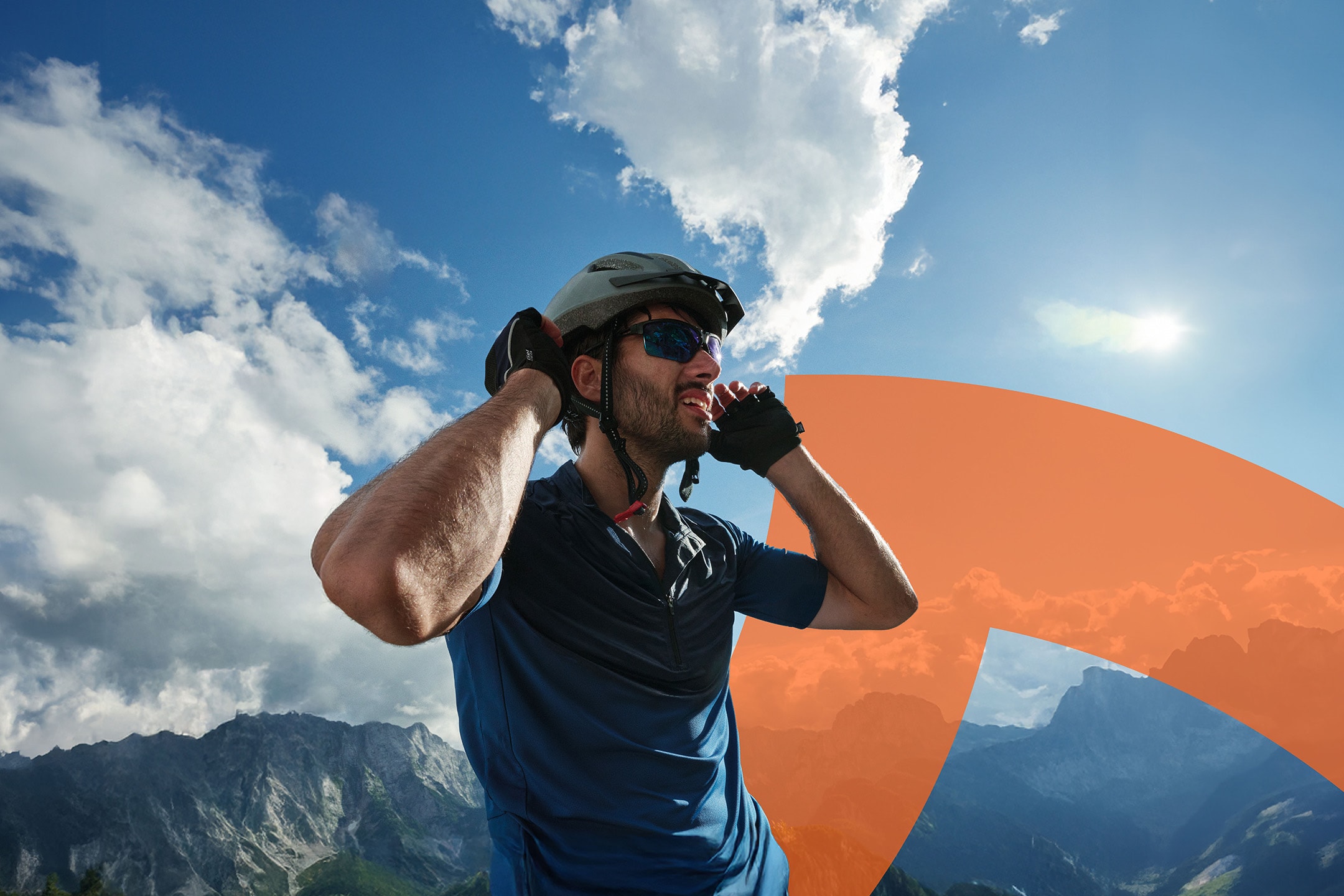 Ciclista con casco e occhiali da sole, in montagna sotto un cielo azzurro.