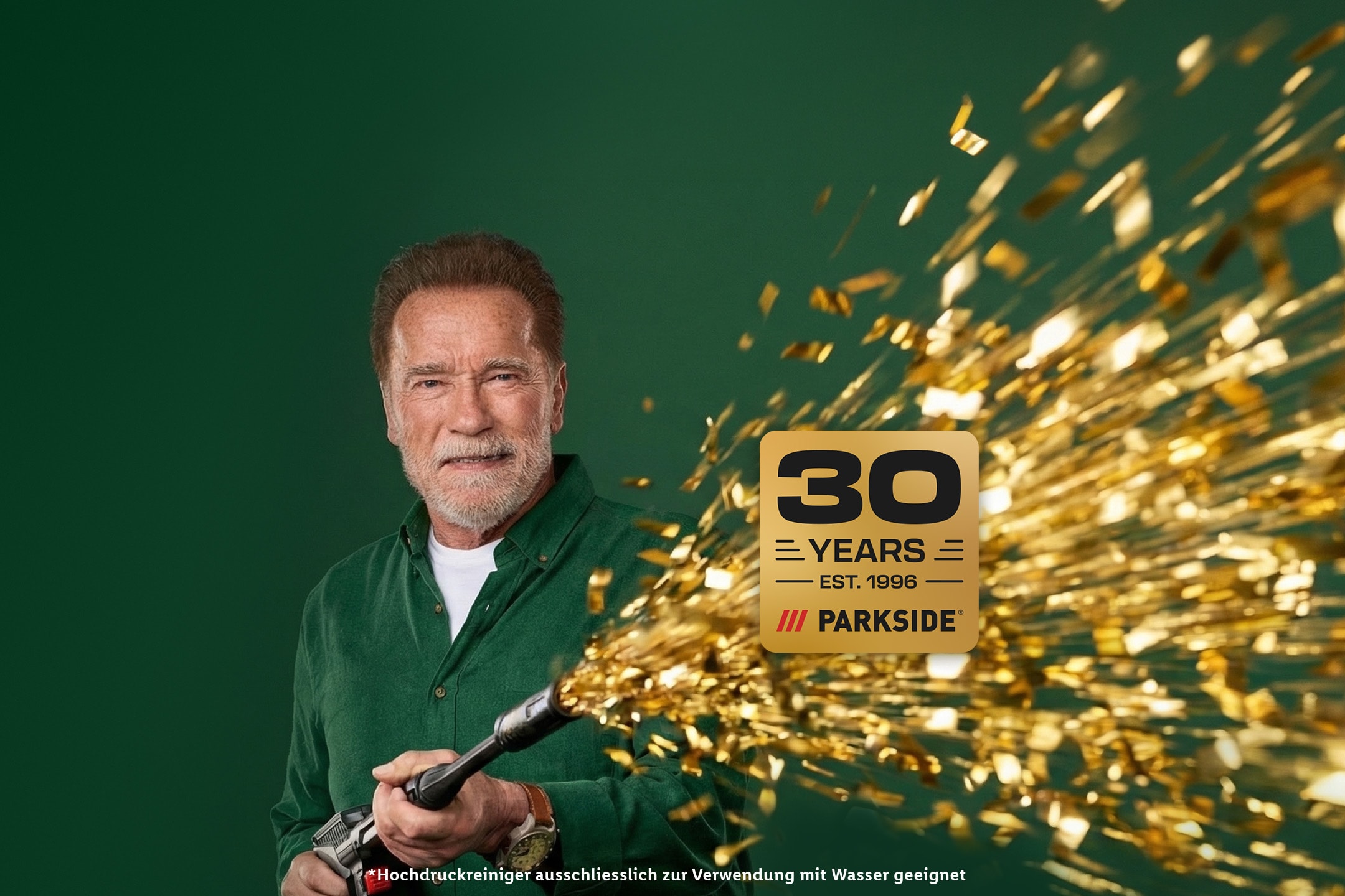 Arnold Schwarzenegger feiert 30 Jahre Parkside mit goldenem Konfetti aus einem Hochdruckreiniger.