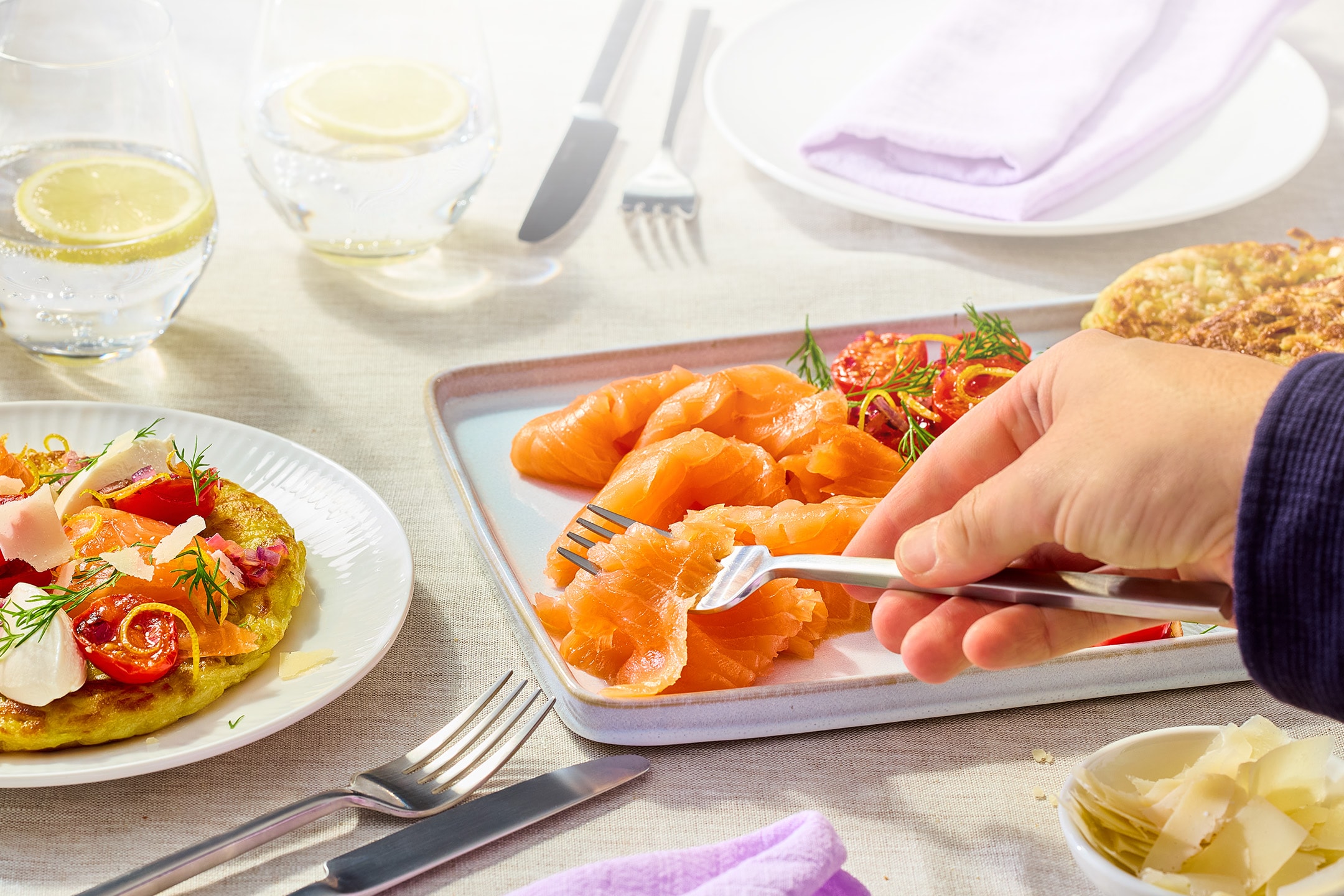 Salmone affumicato con contorni, incluso un pancake di patate, su una tavola apparecchiata.